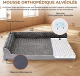 Infographie détaillée d'un lit pour chien orthopédique présenté en coupe transversale sur un sol en bois stratifié. Le lit de style canapé est gris avec des rebords en fausse fourrure texturée. Des légendes en français identifient les composants clés : 'Fausse Fourrure' pour le revêtement, 'Mousse Orthopédique Alvéolée' pour le noyau de soutien (avec un insert de zoom montrant la structure d'œuf et des flèches de circulation d'air), et 'Base Antidérapante' pour le dessous. Le texte principal en haut détaill