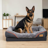 Berger allemand assis dans un grand panier orthopédique gris anthracite avec rebords rembourrés et bordure orange, dans un salon moderne au parquet clair