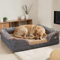 Labrador doré endormi dans un panier orthopédique grande taille gris avec rebords rembourrés et bordure orange, posé dans un salon moderne