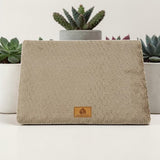 Lit orthopédique beige Happy Animalia en tissu bouclette texturé avec badge cuir, entouré de plantes succulentes sur fond blanc.