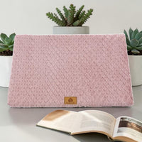 Lit orthopédique rose Happy Animalia en tissu bouclette texturé avec badge cuir, entouré de plantes succulentes et livre ouvert, fond blanc.