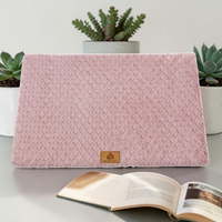 Lit orthopédique rose Happy Animalia en tissu bouclette texturé avec badge cuir, entouré de plantes succulentes et livre ouvert, fond blanc.