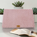 Lit orthopédique rose Happy Animalia en tissu bouclette texturé avec badge cuir, entouré de plantes succulentes et livre ouvert, fond blanc.